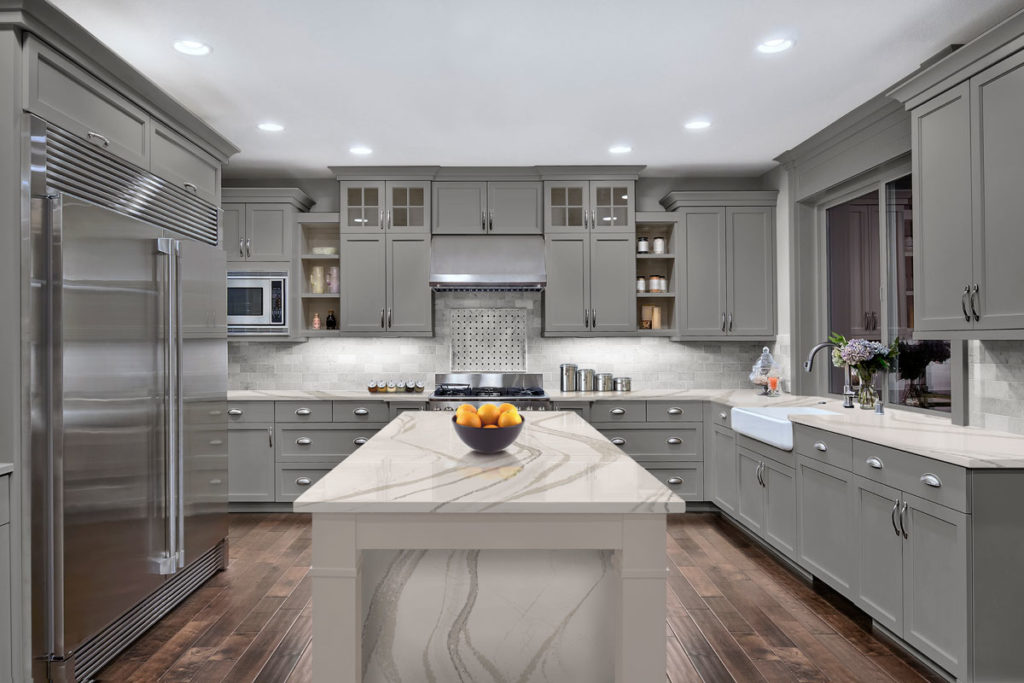 Large kitchen with marble counter top and grey cabinets. 
