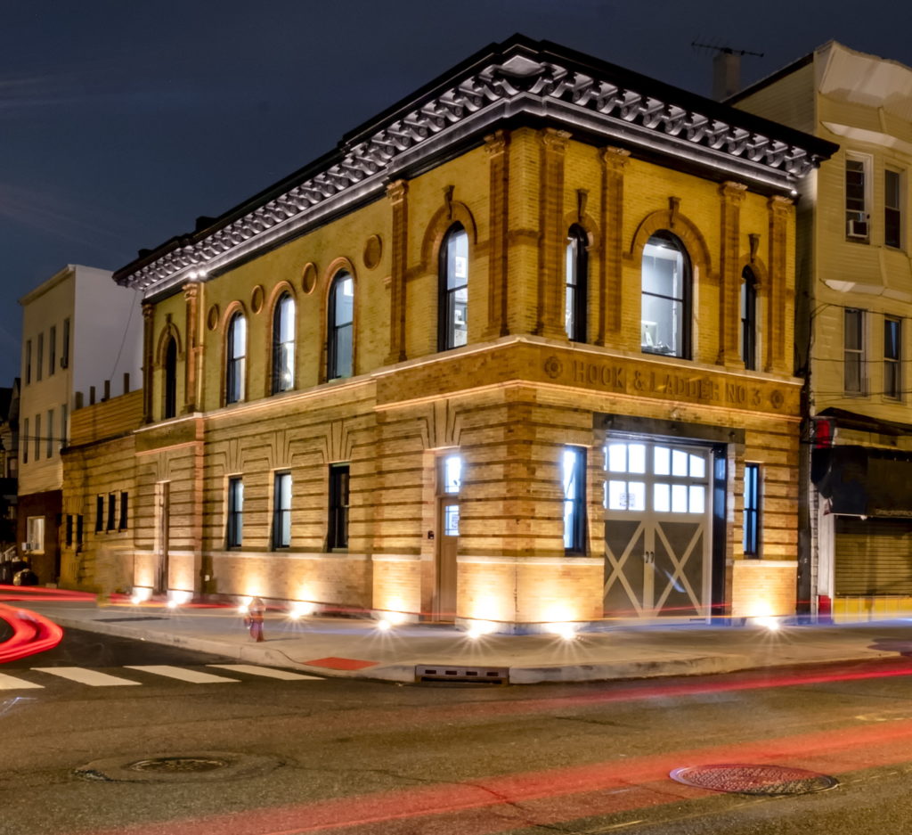 Front facade of an old firehouse at night.