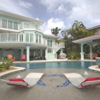 Backyard hangout featuring a pool and pergula, outdoor tv, and large back covered patio