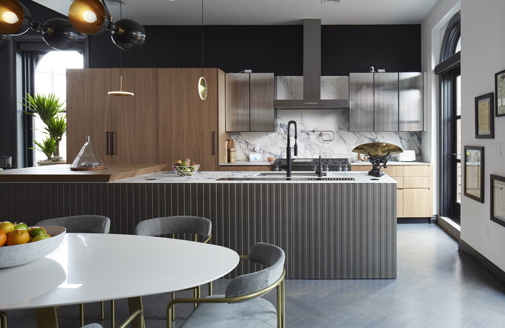 Modern kitchen with stainless steel appliances, marble and black accents with natural wood cabinets.