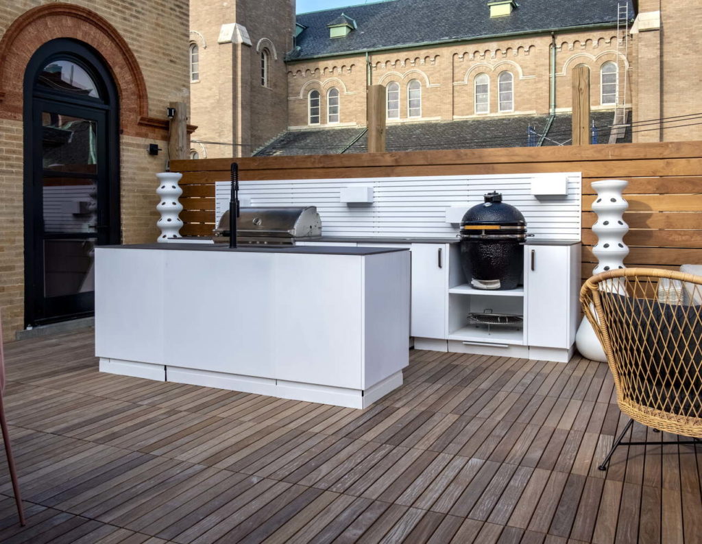 Roof top kitchen with white cabinets, natural brick walls and wood flooring. 