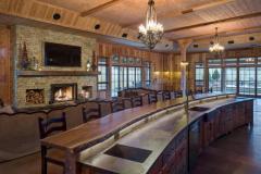 Side view of the bar adorned with a natural wood countertop. It is long and curved almost as if the tree the wood came from was grown especially for this space.